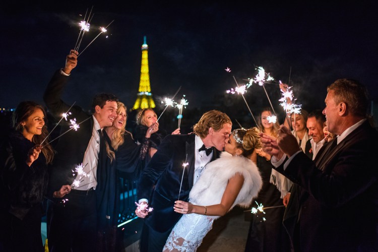 Bride and groom kissing on their wedding night surrounded by close friends and family