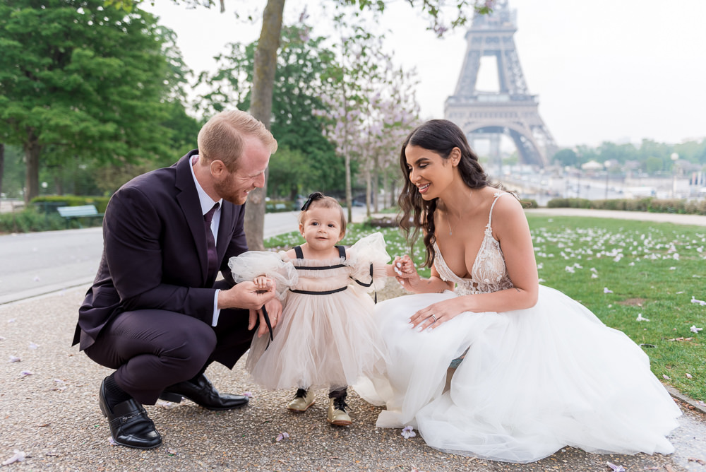 Bride and groom posing with their daughter for elopement photos in front of the Eiffel Tower