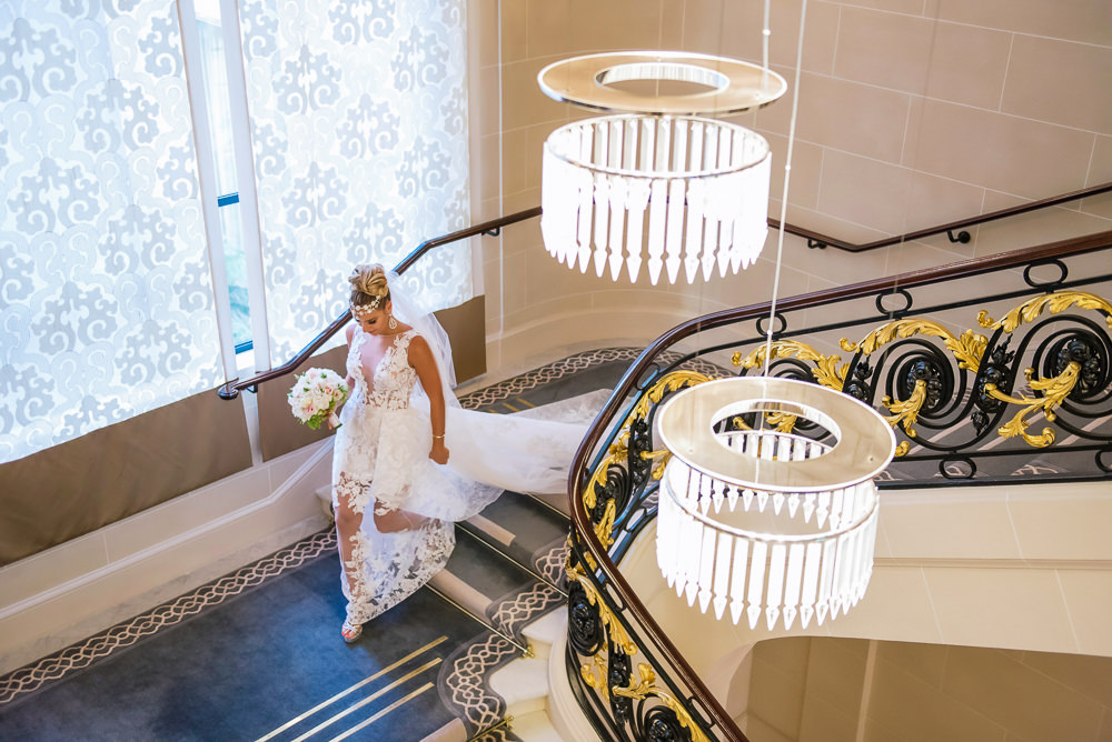 Bride walking down the stairs of her hotel to meet her groom