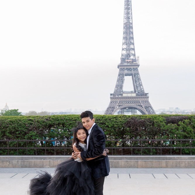 Brother and sister wearing black outfits posing for photos with paris family photographer Daniel