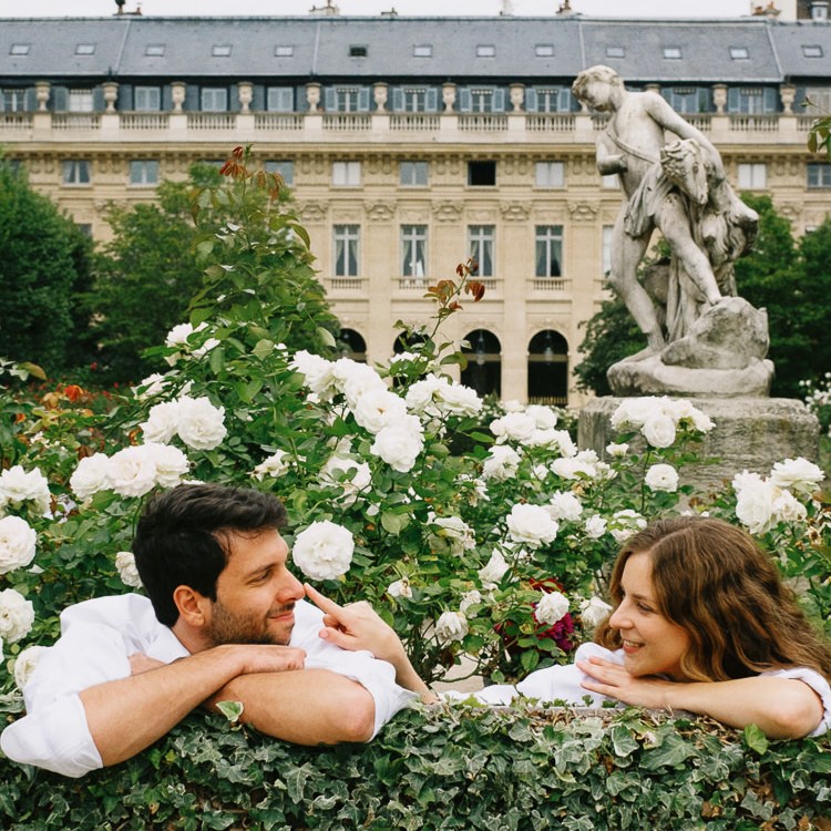 Couple being playful surrounded by white flowers at Palais Royal