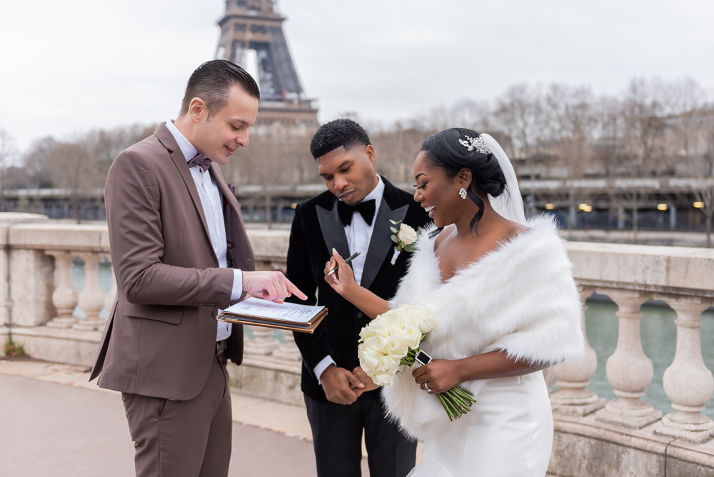 Couple eloping at the Eiffel Tower signing marriage certificate