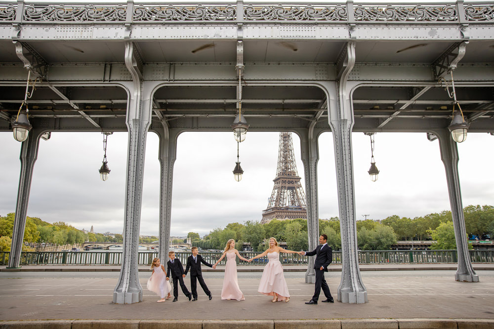 Family of 6 posing for professional photos during the summer of 2024 on the Bir Hakeim bridge overlooking the Eiffel Tower