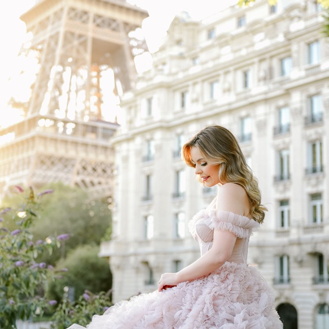 Girl wearing big tulle dress posing for maternity photos by the Eiffel Tower in Paris