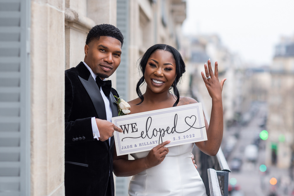 Happy couple holding WE ELOPED sign after theit wedding in Paris