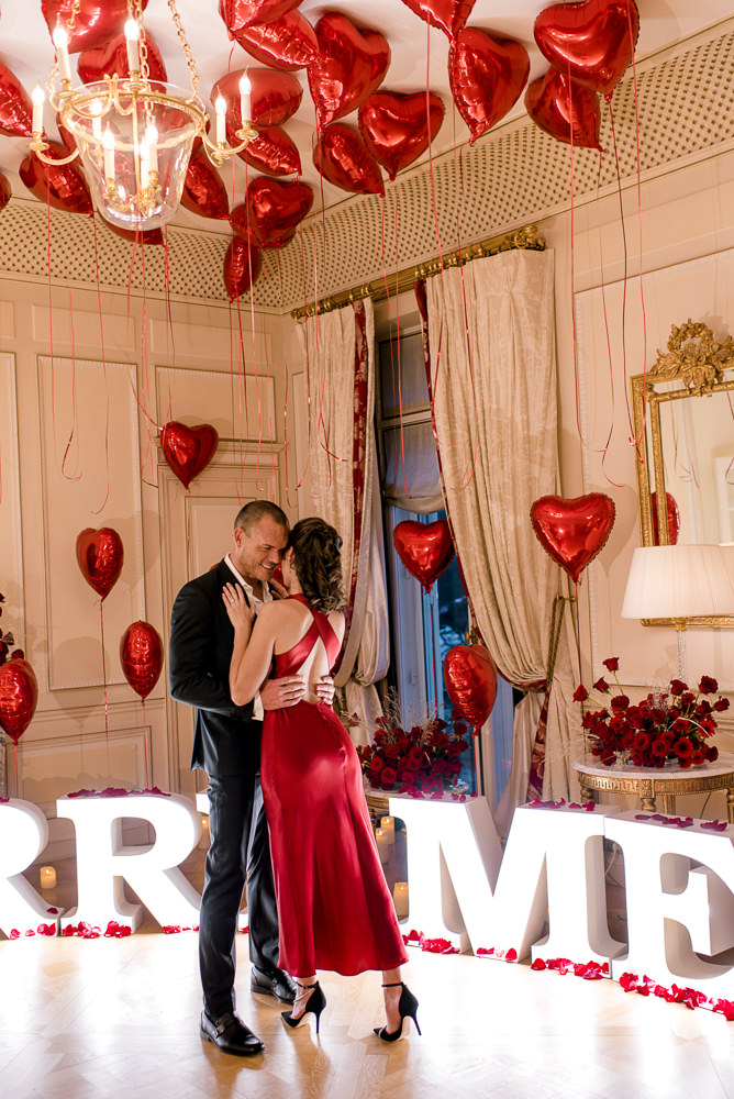 Hotel proposal in Paris with Marry Me Letters and red heart shaped balloons