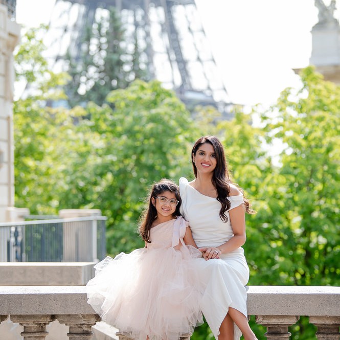 Mother and daughter in white dresses posing for professional family photographer Odrida at the Eiffel Tower