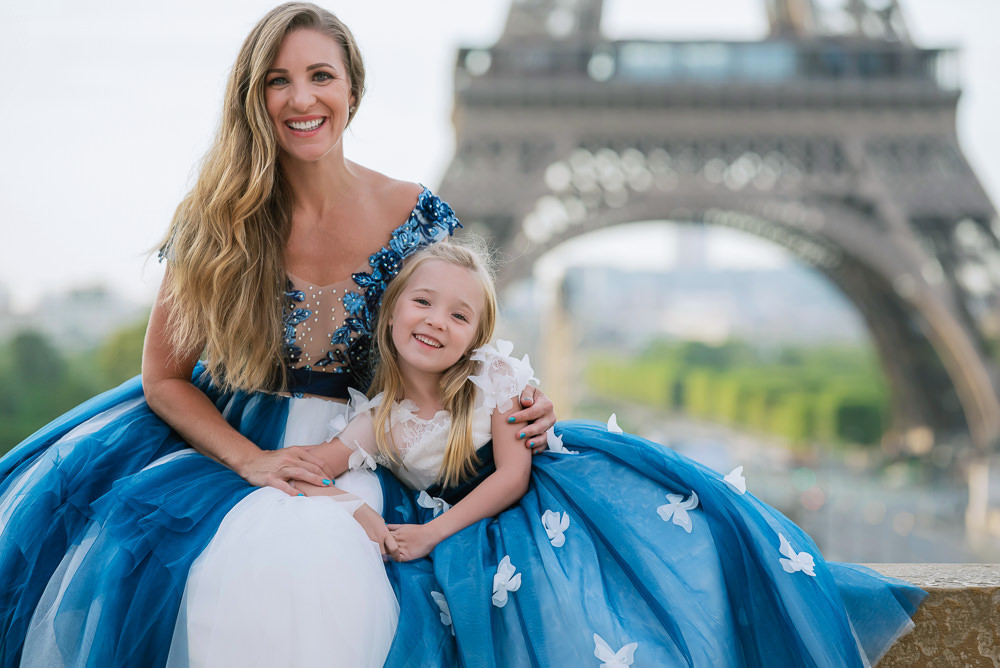 Mother and daughter with matchy blue outfits posing for professional photos in front of the Eiffel Tower