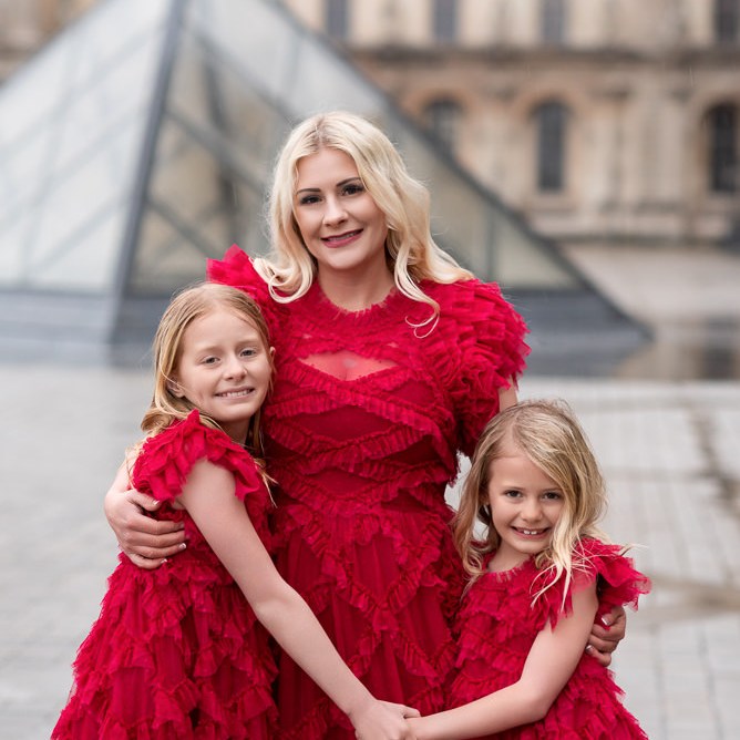 Mother and daughters wearing fabulous red dresses taking family photos at the Louvre with Odrida