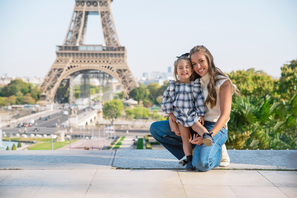 Mother holding daughter in her arms in front of the Eiffel tower