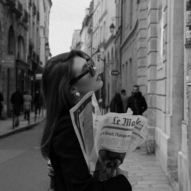 Stylish woman posing for fashion photos with Le Monde newspaper in the streets of Paris